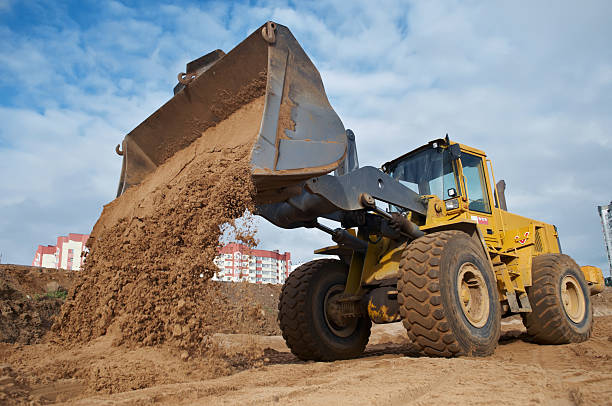 Wheel loader machine unloading sand at eathmoving works in construction site